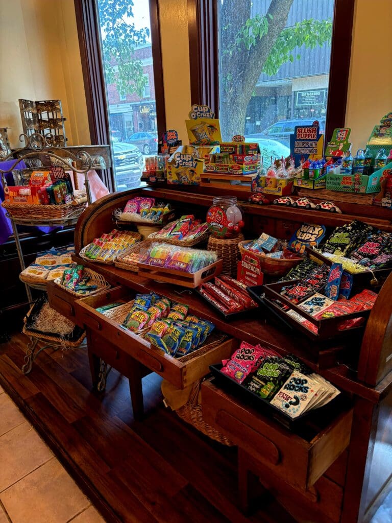 An overhead view of a retail display featuring multiple tables arranged with colorful toy and action figure collections in a warm, wood-toned shop with large windows.