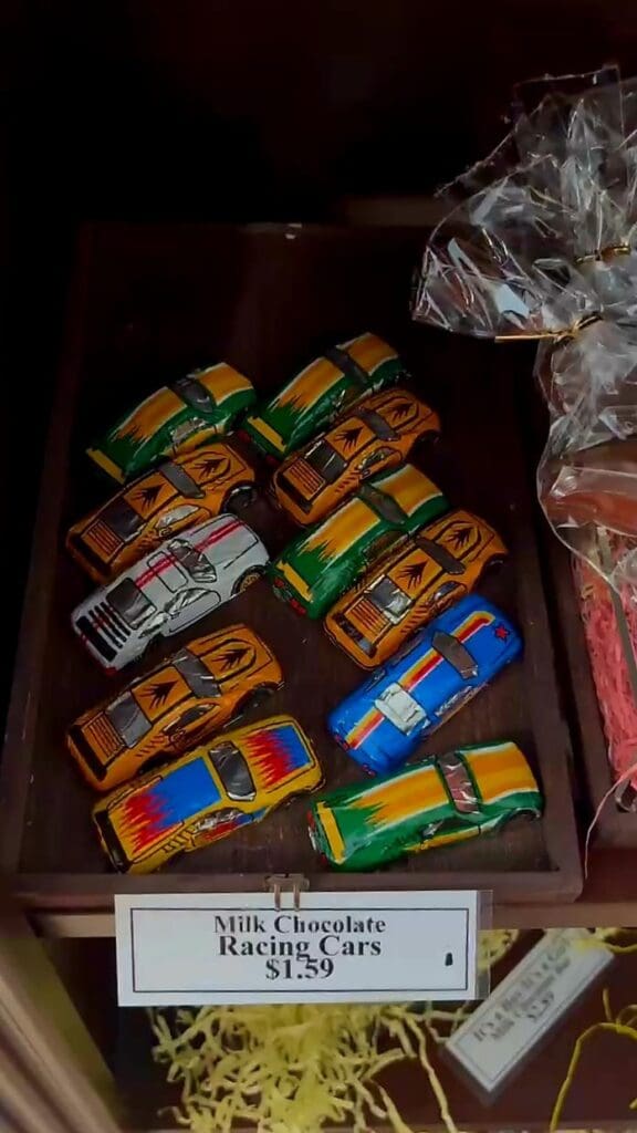 A collection of colorful toy cars displayed in a bin with a price tag reading '$1.99', photographed from above in an indoor retail setting.
