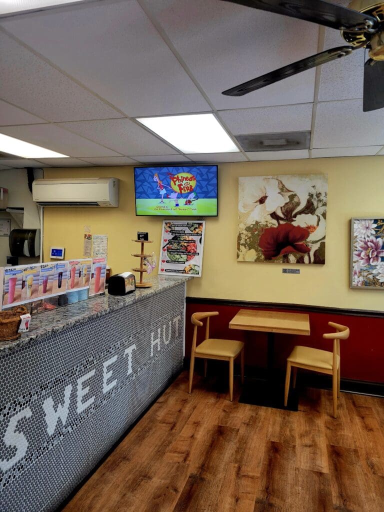Interior view of a pet store or aquarium shop featuring a service counter, merchandise displays, and a TV mounted on the wall.