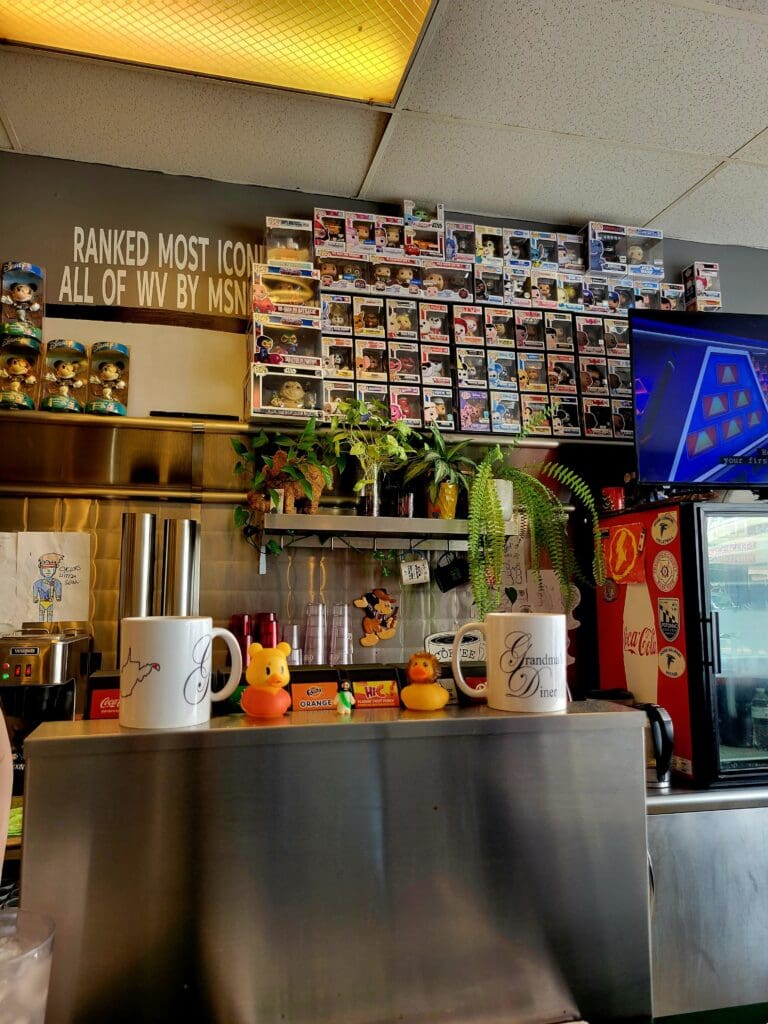 A cozy coffee shop interior featuring a counter with espresso machines, shelves stocked with packaged goods, and warm ambient lighting creating an inviting cafe atmosphere.