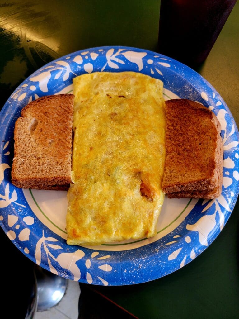 A breakfast plate with an omelet and two slices of toast arranged on a blue and white decorative ceramic plate.