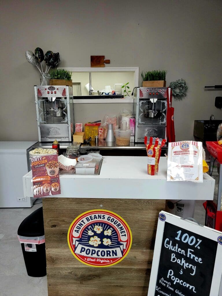 A vintage-style popcorn stand with shelving, a popcorn machine, and carnival signage displayed indoors.