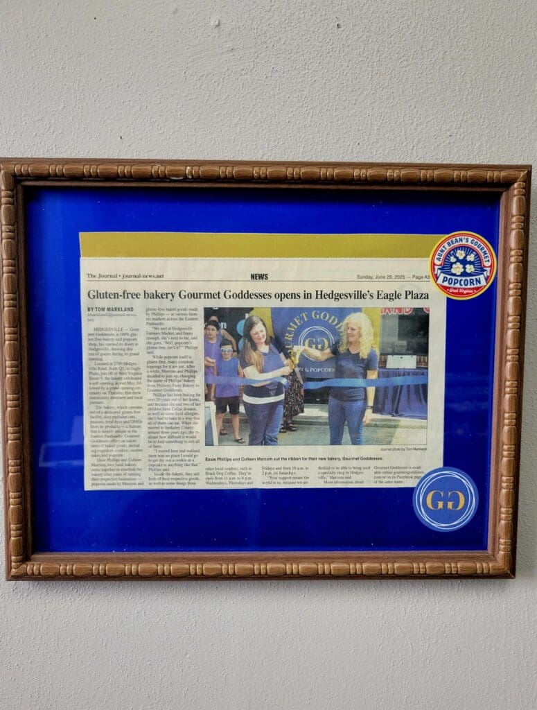 A framed newspaper clipping mounted on a blue mat with a wooden frame and official seals, displaying what appears to be a commemorative or award presentation article with accompanying photograph.