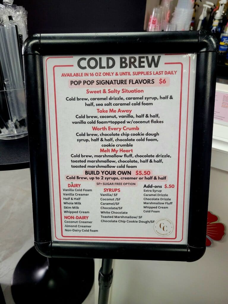 A framed instructional sign for making cold brew coffee mounted on what appears to be a black beverage dispenser or container.