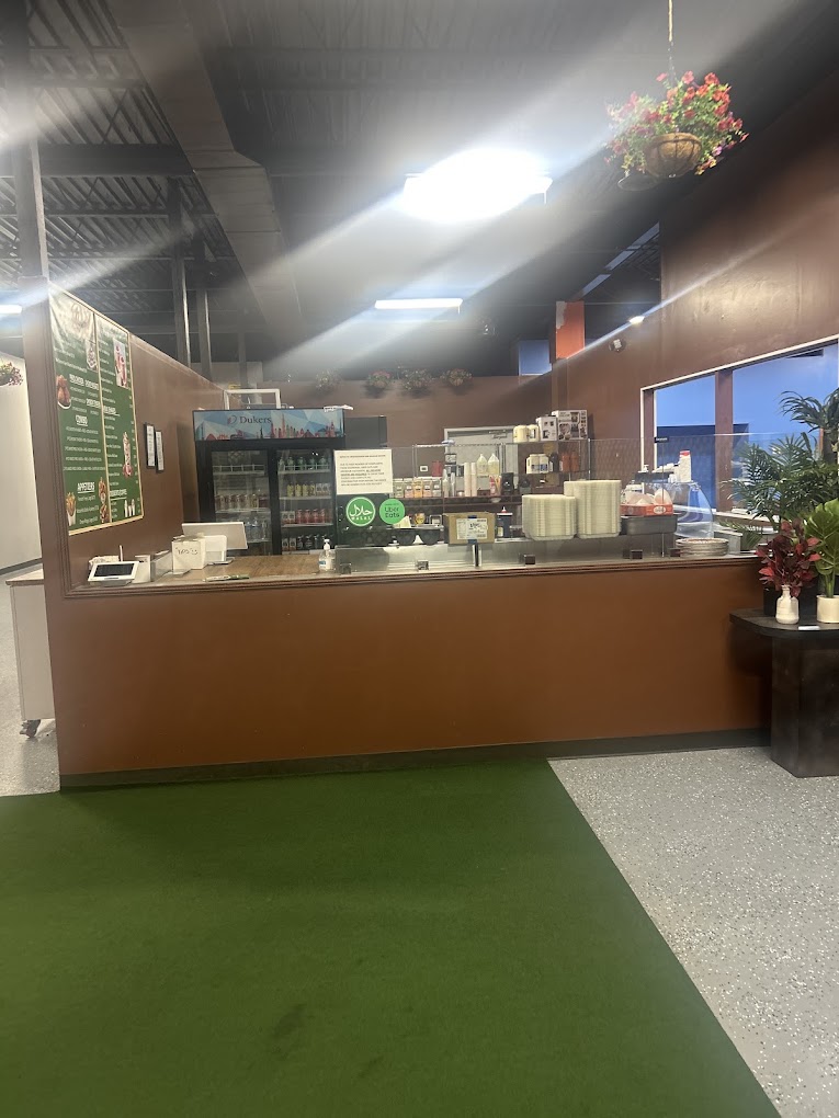 An indoor retail or exhibition venue with a brown counter, artificial green flooring, and overhead lighting creating a modern commercial space.