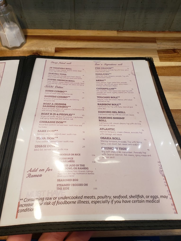 A laminated restaurant menu displayed on a wooden table in an indoor dining setting.