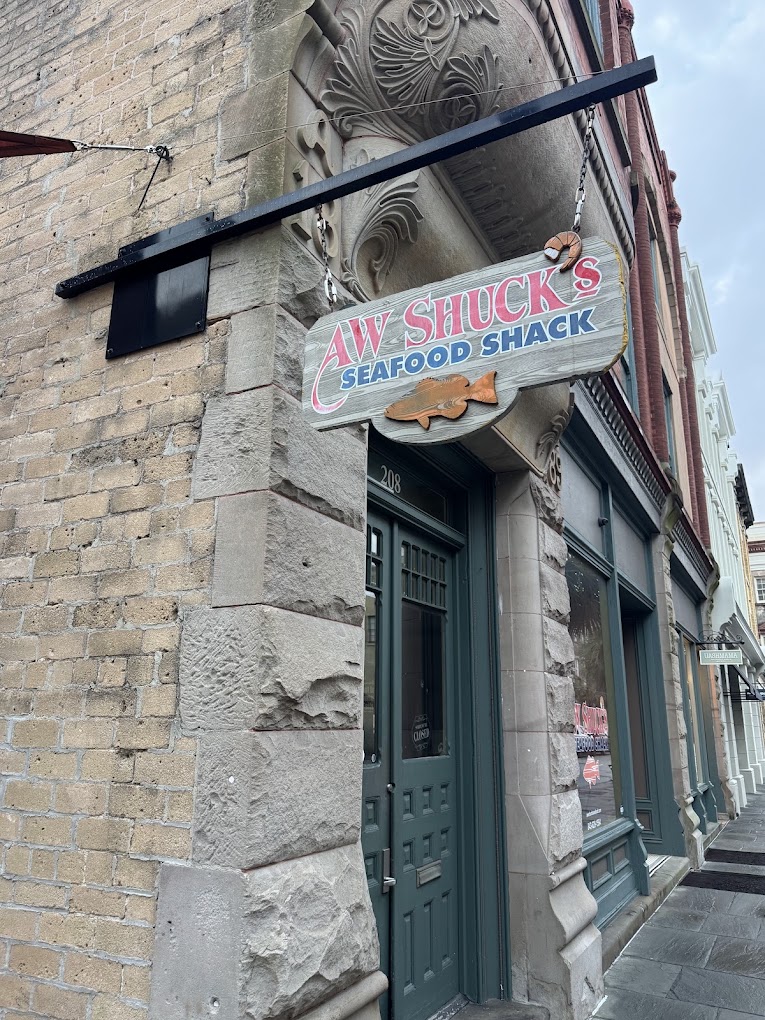 A traditional fish and chips shop storefront on a brick building with a painted sign and shop window, photographed during daytime.