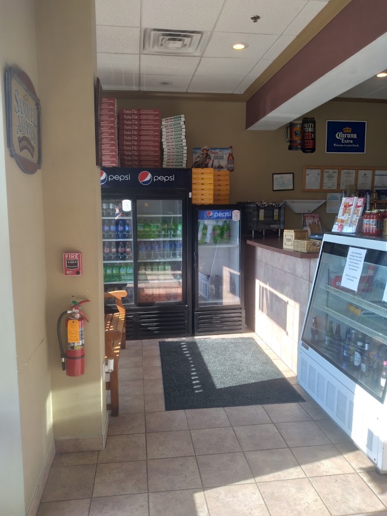 An empty convenience store interior with refrigerated beverage cases, entrance mat, and overhead lighting in a neutral color palette.