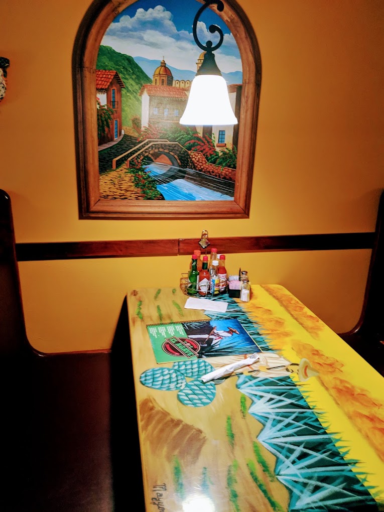 A colorful arcade or gaming table sits in a warmly-lit indoor venue with southwestern-themed artwork and dรฉcor on the walls.