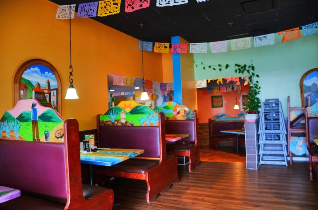 A brightly colored indoor children's play and learning space featuring orange walls, colorful furniture, toy storage units, and educational play areas designed for young learners.