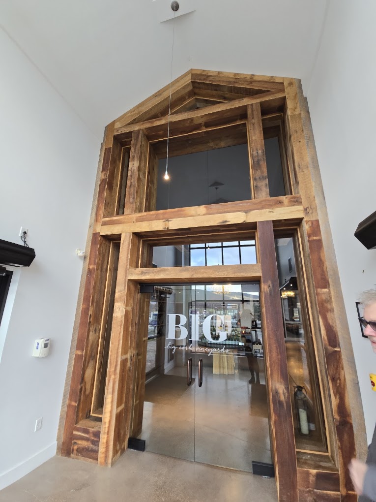 A wooden door frame with glass doors in an interior construction or renovation setting, showing modern architectural elements in a neutral indoor environment.