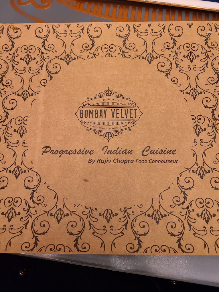 A vintage cookbook cover for 'Progressive Indian Cuisine' by Surbat Velvet features ornate decorative scrollwork patterns in warm tan tones with centered typography.