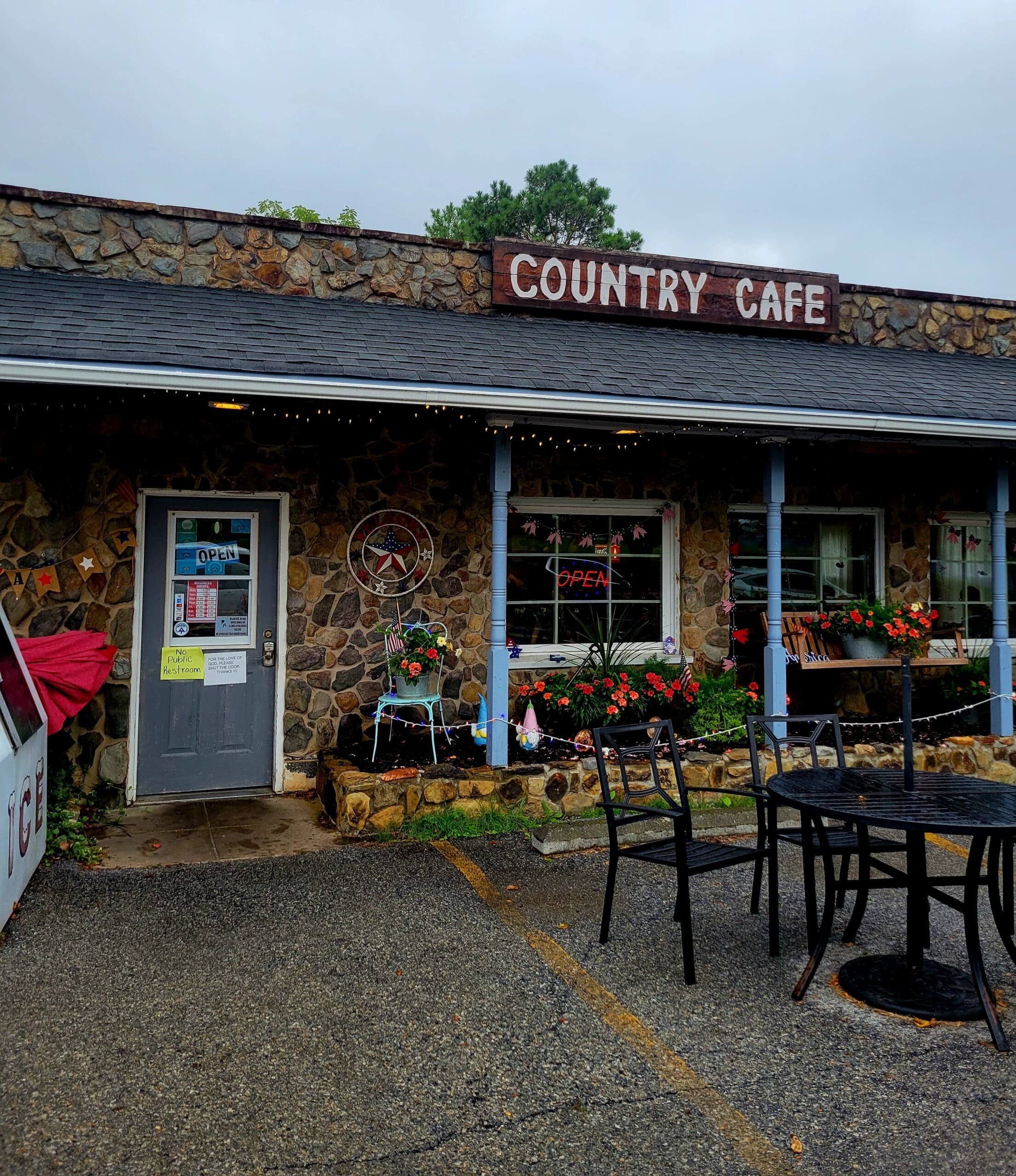 A charming country cafe with rustic charm features outdoor seating with flowers and weathered wooden signage.
