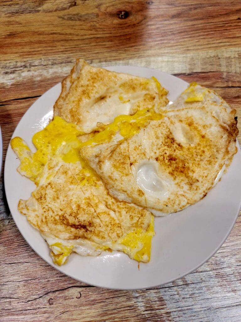 Three golden omelets filled with cheese and herbs are served on a white plate on a wooden table.