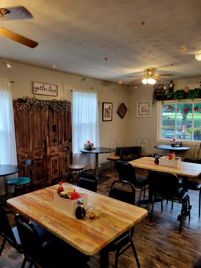 A bright, organized workshop or creative studio space with wooden tables, comfortable seating, and natural light from large windows.
